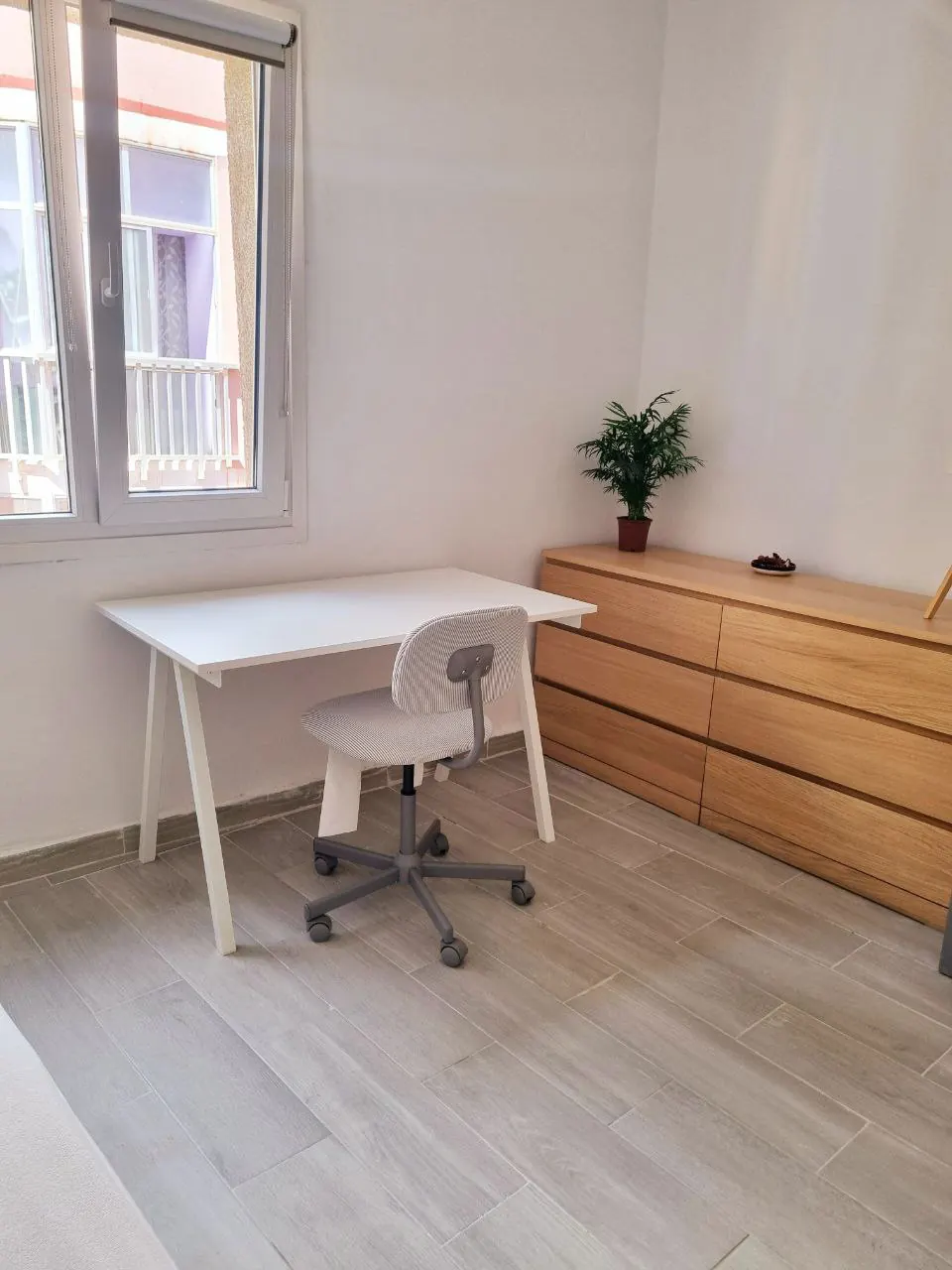 Habitación con escritorio, silla y cómoda junto a la ventana